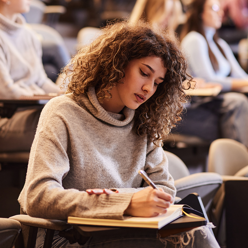 A woman taking notes in a classroom