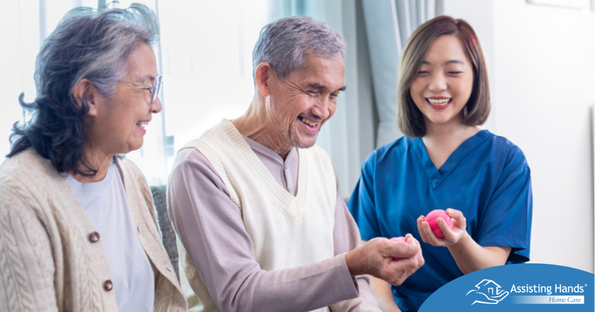 A compassionate caregiver engages a senior couple in a gentle, hands-on activity designed to promote coordination and well-being. Assisting Hands Home Care proudly serves Lexington, MA families by providing personalized care that supports both physical health and emotional connection.