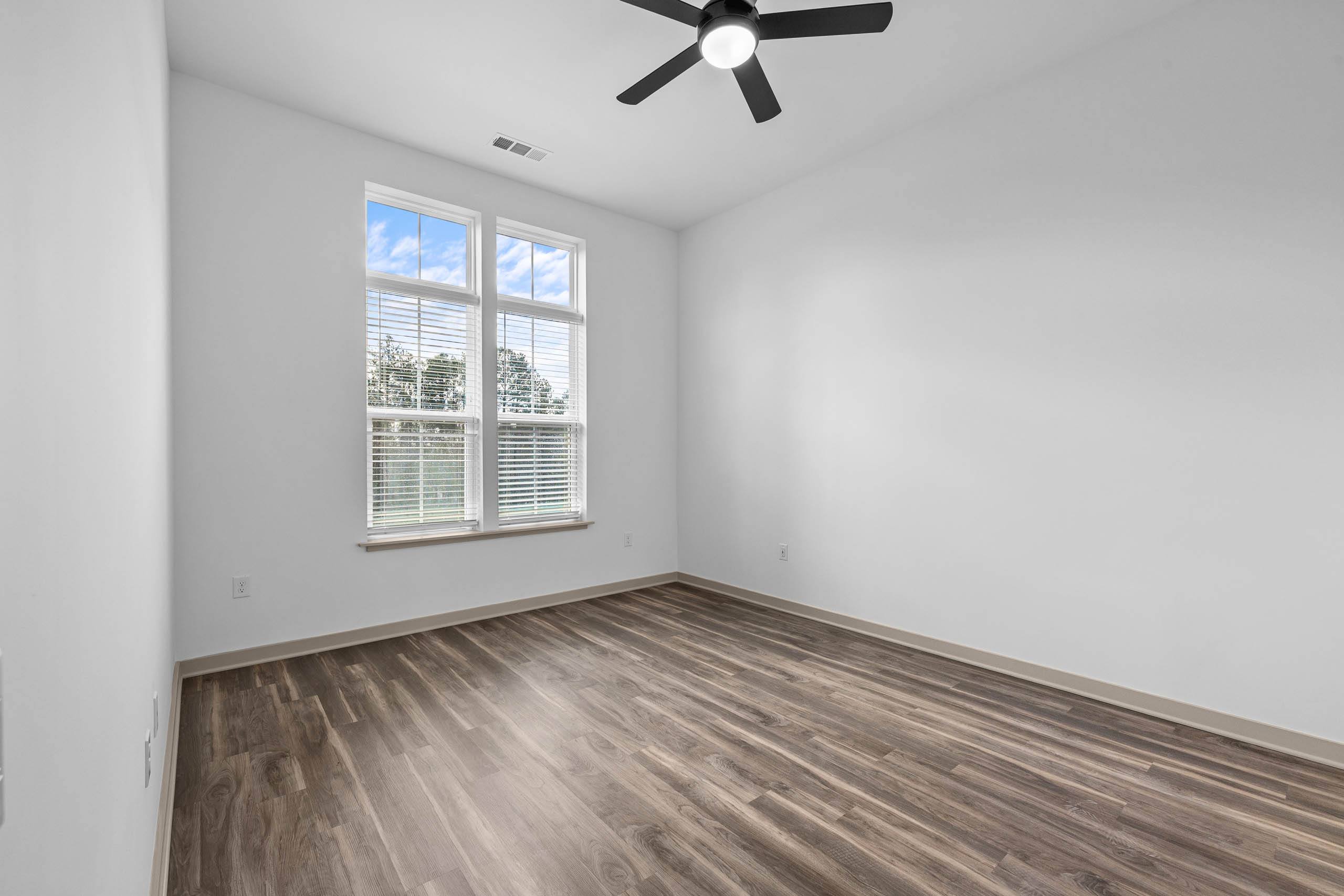 A room with a ceiling fan and a window with blinds