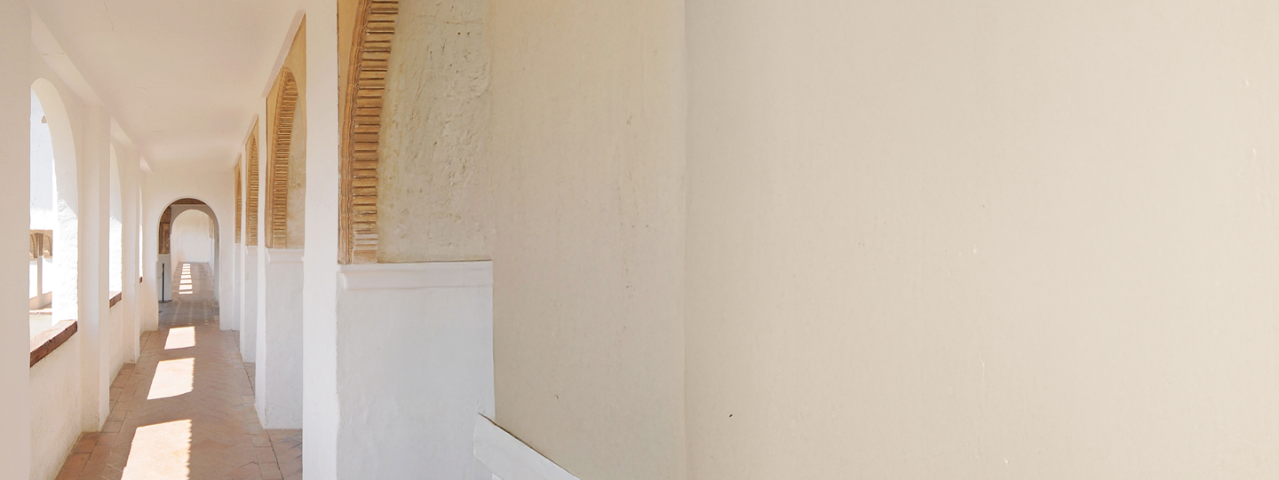 An open-air corridor with warm light shining through.