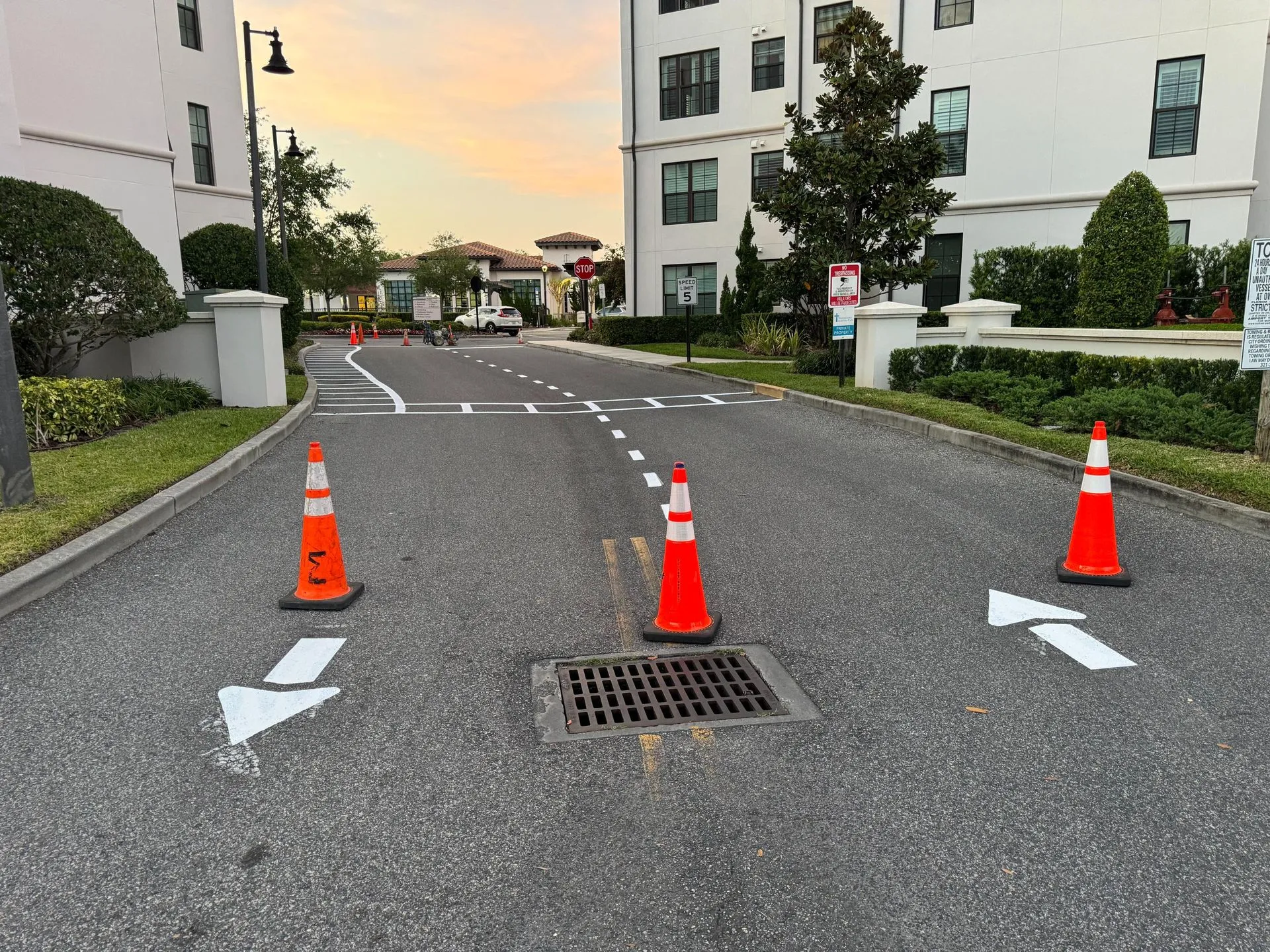 Fresh roadway striping and directional arrows surrounding a storm drain entrance, showcasing professional pavement marking and traffic control improvements in a residential property setting.