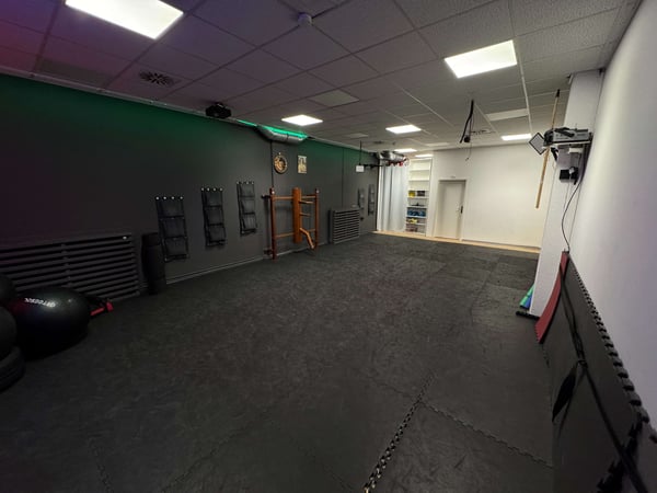 TA WingTsun Seelze - Weitläufiger Übungsraum mit Mattenboden, Trainingsgeräten, Wandpolstern und klassischer Holztrainingspuppe für effektives Selbstverteidigungstraining und Kampfkunst.