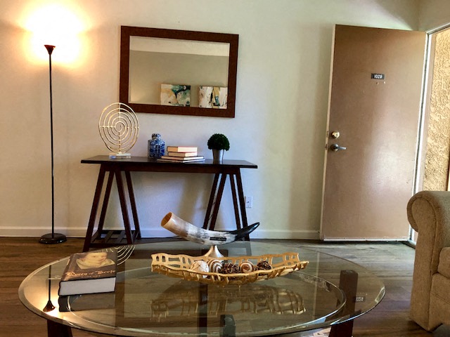 A glass table with a lamp and a mirror on the wall.