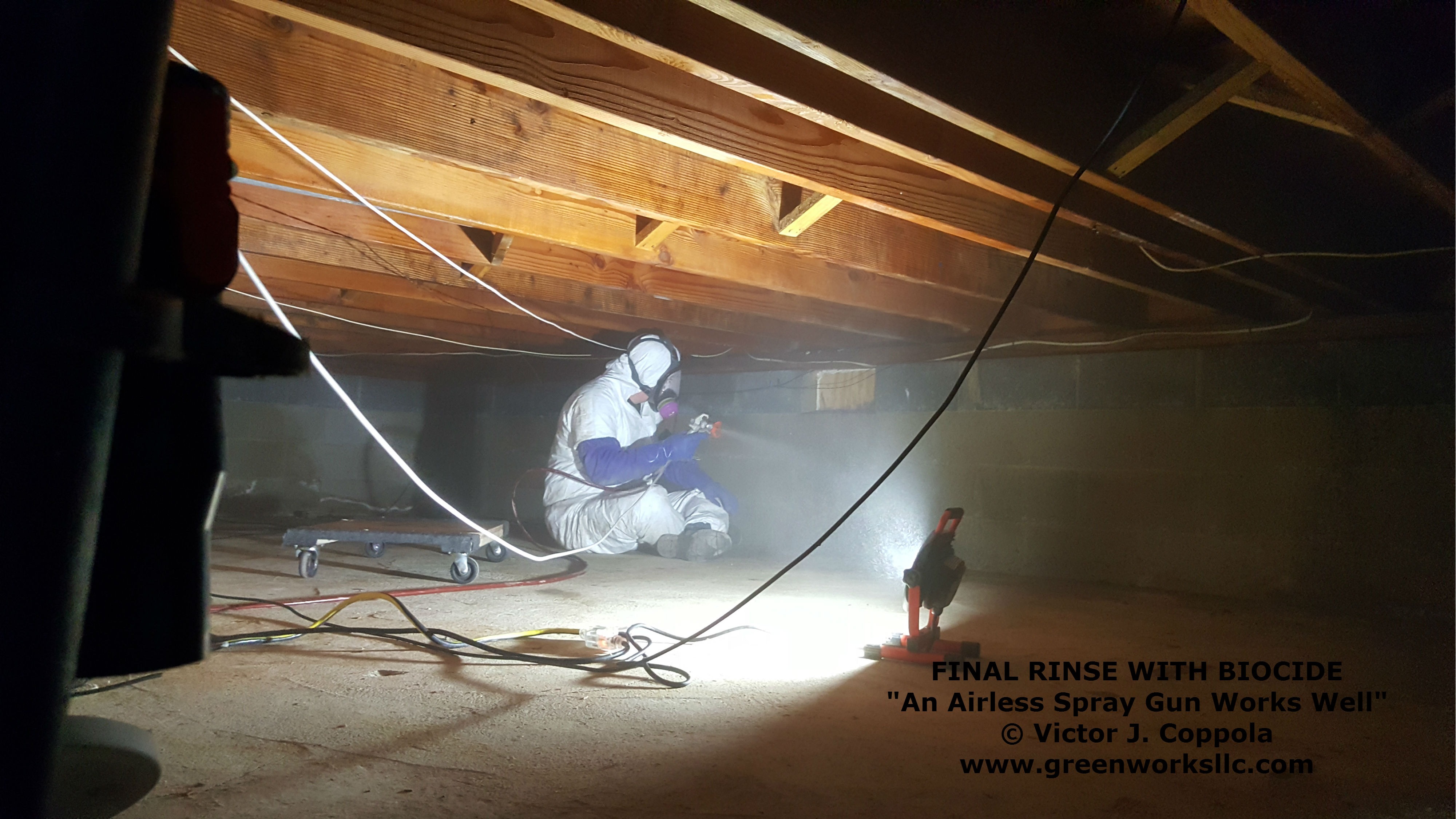 Crawl space treatment photo showing an airless sprayer being used to apply biocide to affected wood and structural materials.