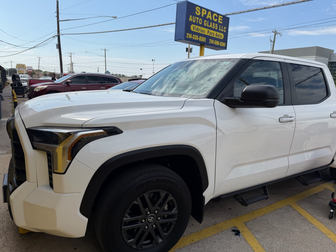 A white Toyota truck shown outside Space Auto Glass with its windshield and side glass in place. The completed vehicle demonstrates professional auto glass replacement service for larger trucks.