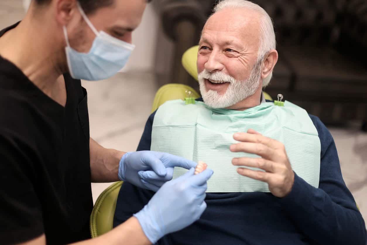 An Absolute Dentist patient smiling while talking to the dentist about limiting tooth loss.