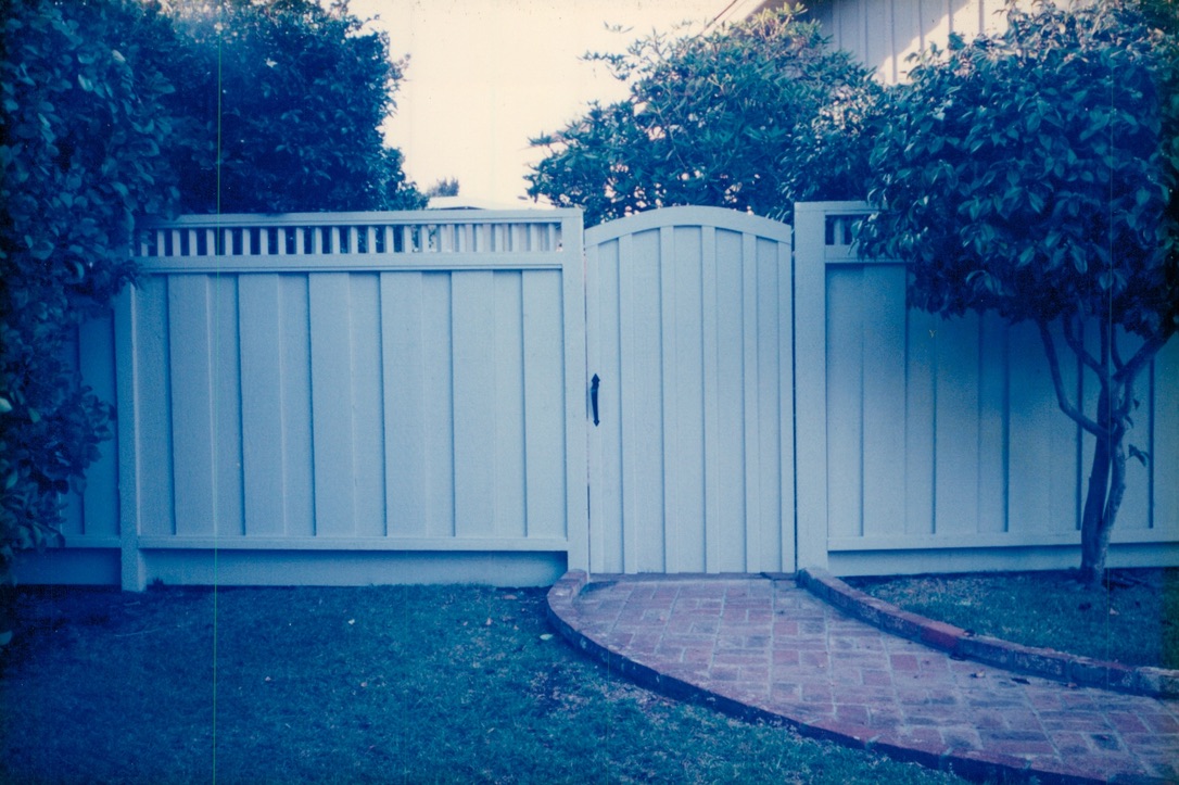 White vinyl privacy fence with a double gate installation providing secure backyard access and a clean modern appearance.