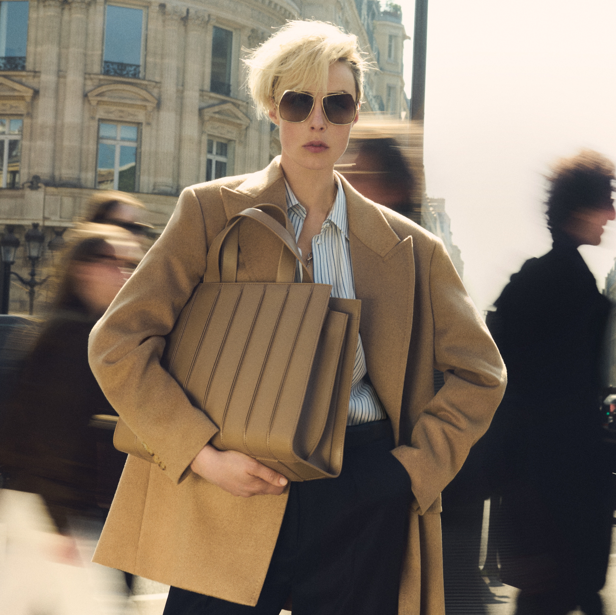 Mannequin portant le blazer double boutonnage Olimpia Jacket de Max Mara couleur chameau, avec des lunettes de soleil et avec sac Whitney Bag 7 de Max Mara grand format, en cuir couleur chameau avec surpiqûres verticales en relief.