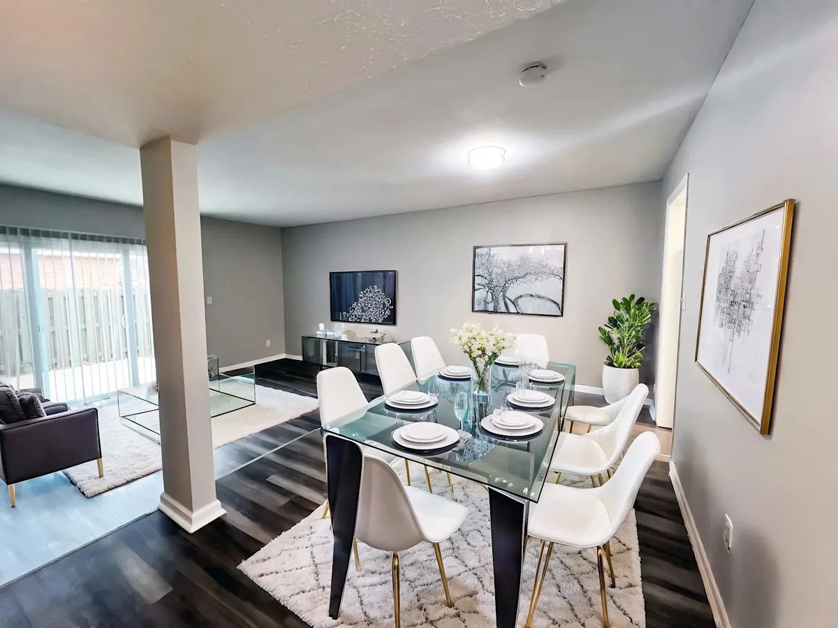 A dining room with a glass table and white chairs