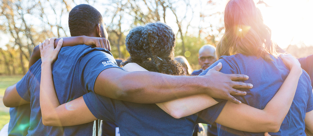 People in blue t-shirts standing side by side in a huddle.