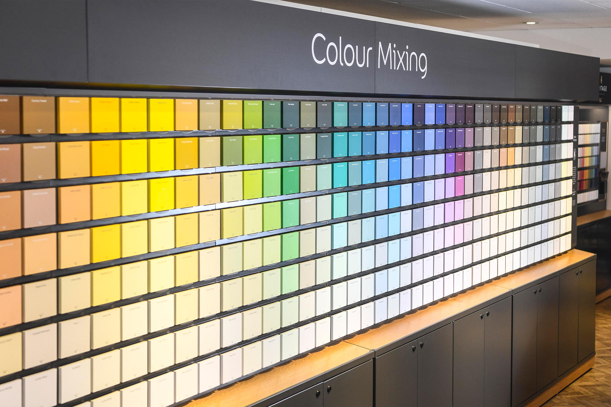 A colour mixing wall at a Homebase store. Square colour chips are hung on a wall show a variety of shades from light to dark.
