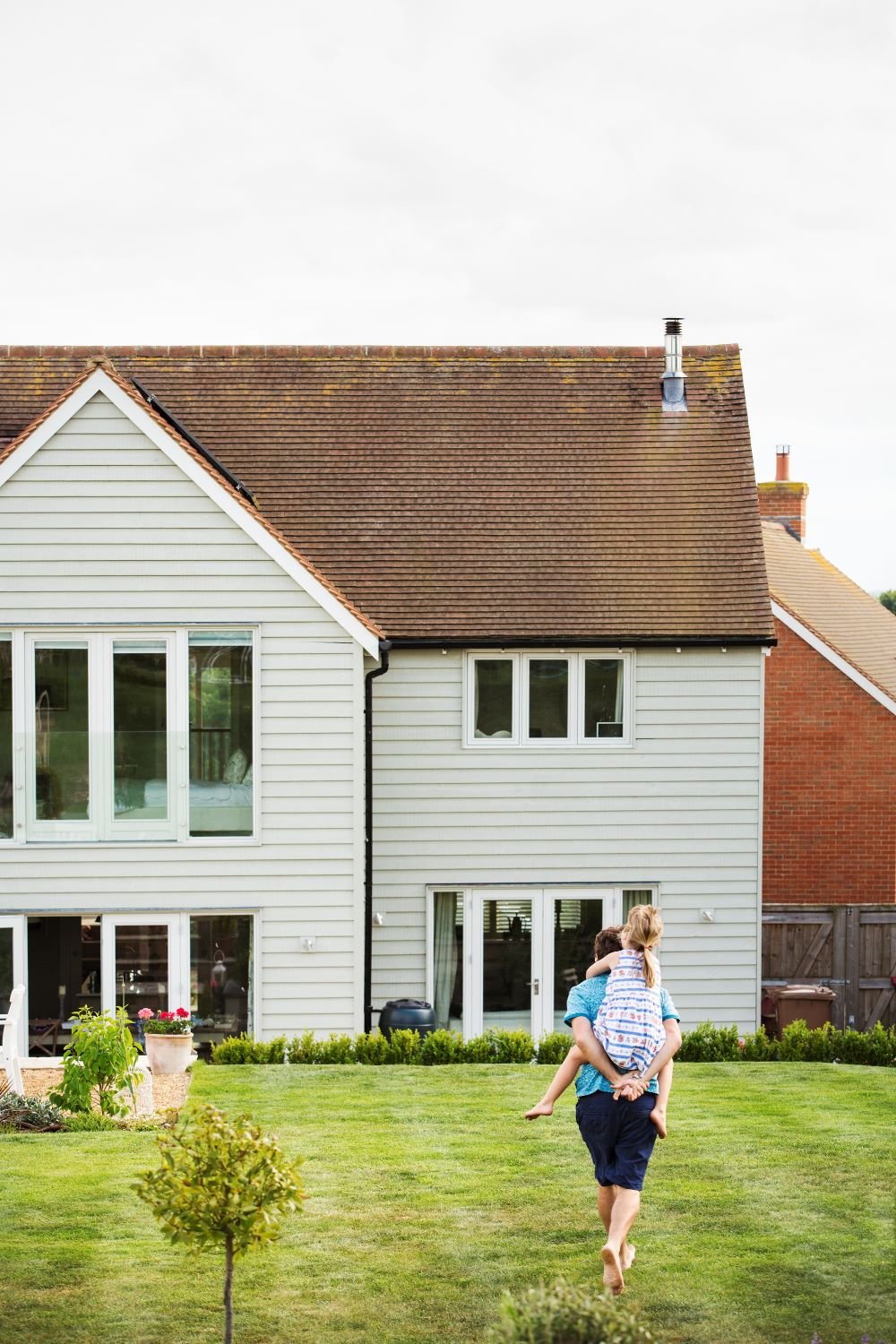 Large home with siding installation and man standing in front yard
