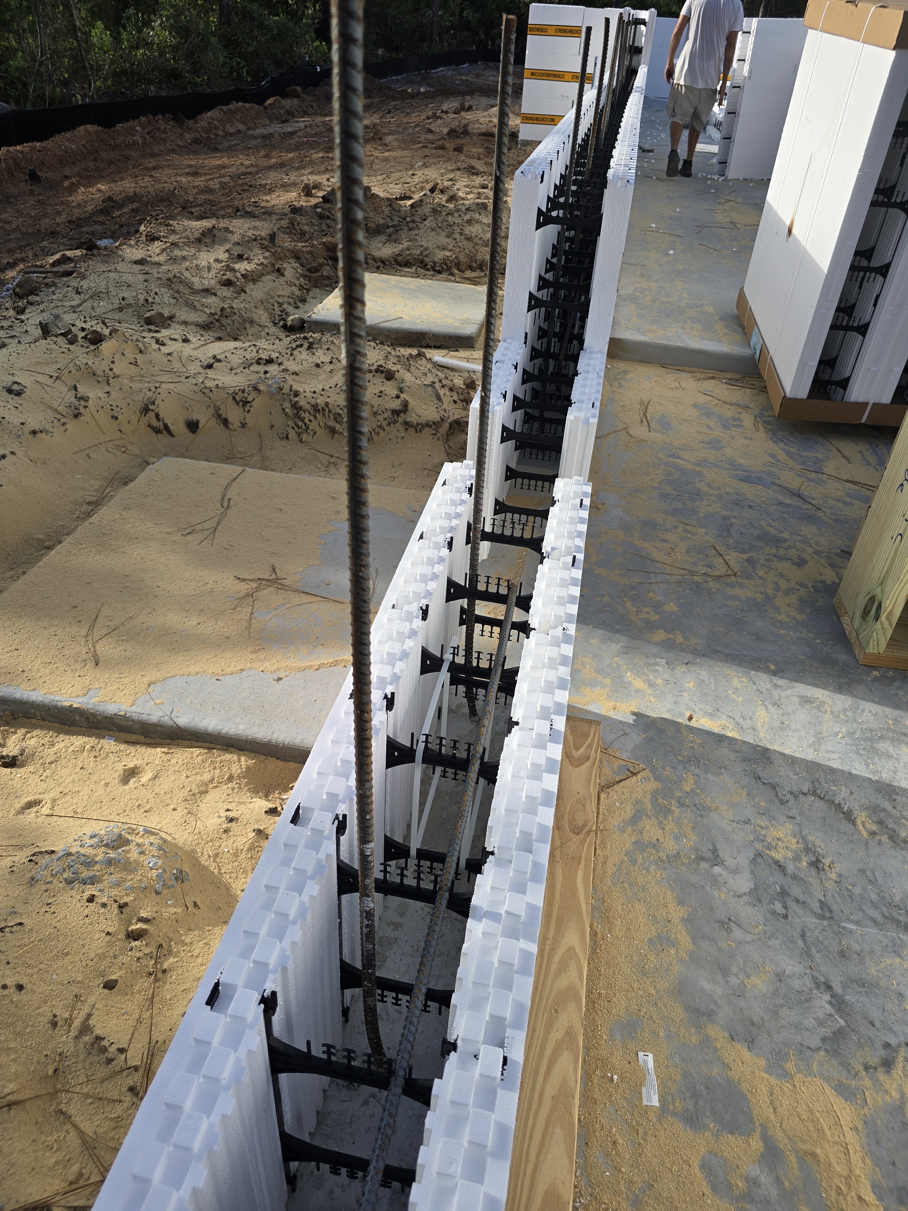 A construction site featuring rows of white insulated concrete forms (ICFs) being prepared for pouri 