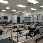 Professional Pilates studio featuring multiple reformer machines in a bright, spacious environment. Our fully-equipped studio provides a clean, modern setting for personalized Pilates training and core strength development.