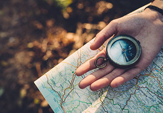 Close-up of a person holding a compass and map in a hand.