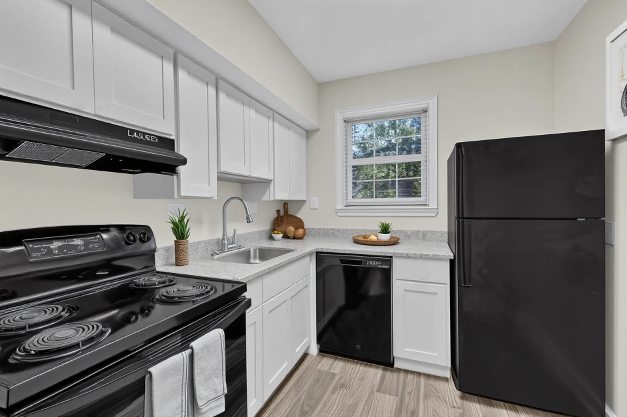 A black stove top oven sits in a kitchen with white cabinets.
