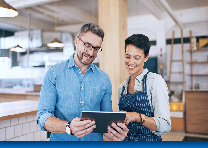 Two business owners reviewing information on a tablet.
