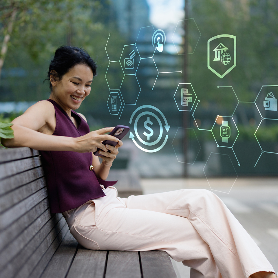 A woman sitting on a bench typing on her phone.