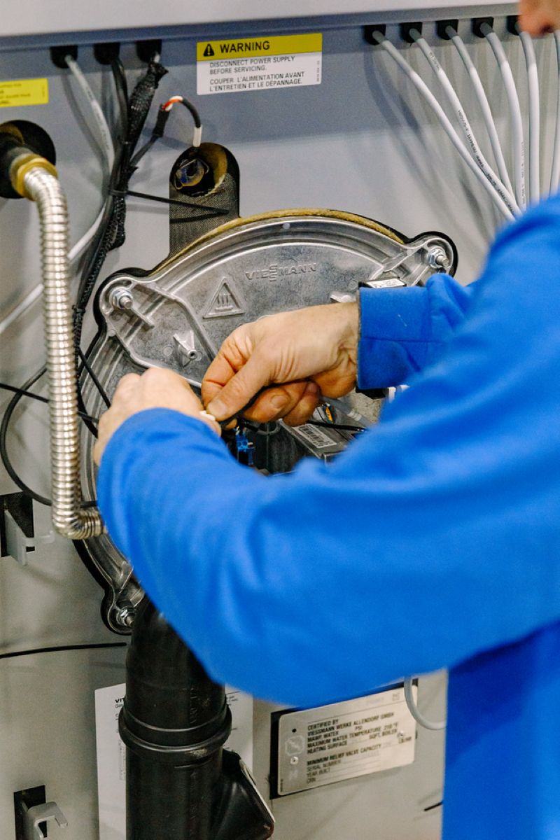 A Beaupre Fuels HVAC technician performing maintenance on a residential heating system in Southern Maine. Beaupre Fuels provides expert boiler repair, furnace maintenance, heating system installation, and HVAC services for homes and businesses throughout the region.