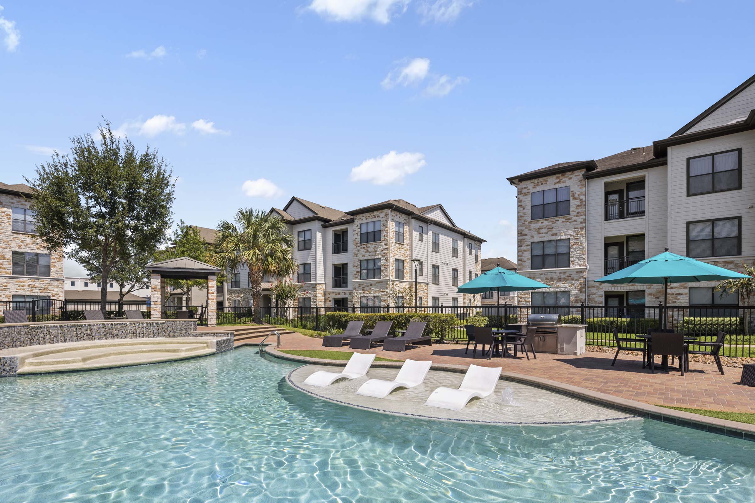 Resort-style pool with tanning shelf grills and dining areas