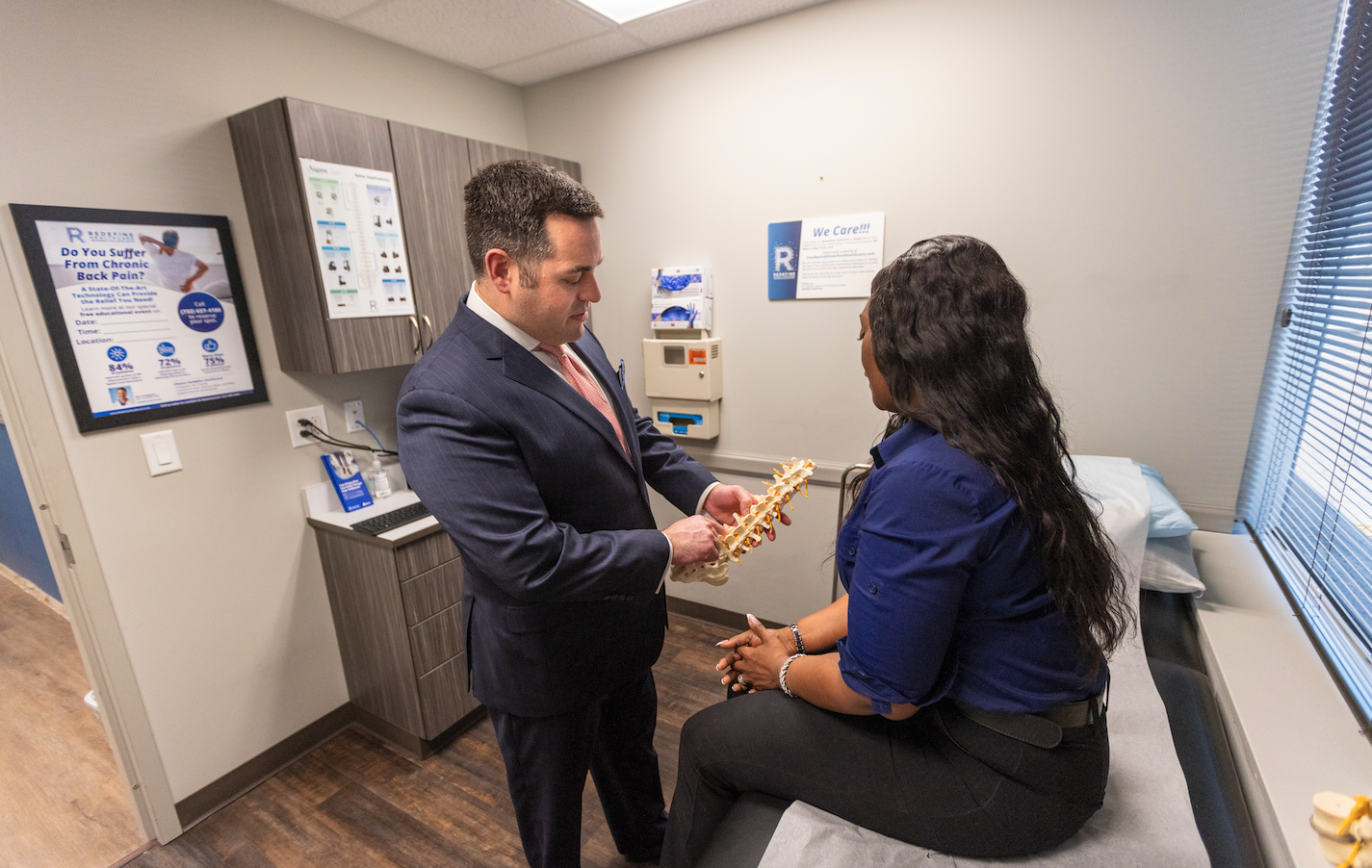 Dr. Aaron J. Greenberg in exam room with patient holding spine model
