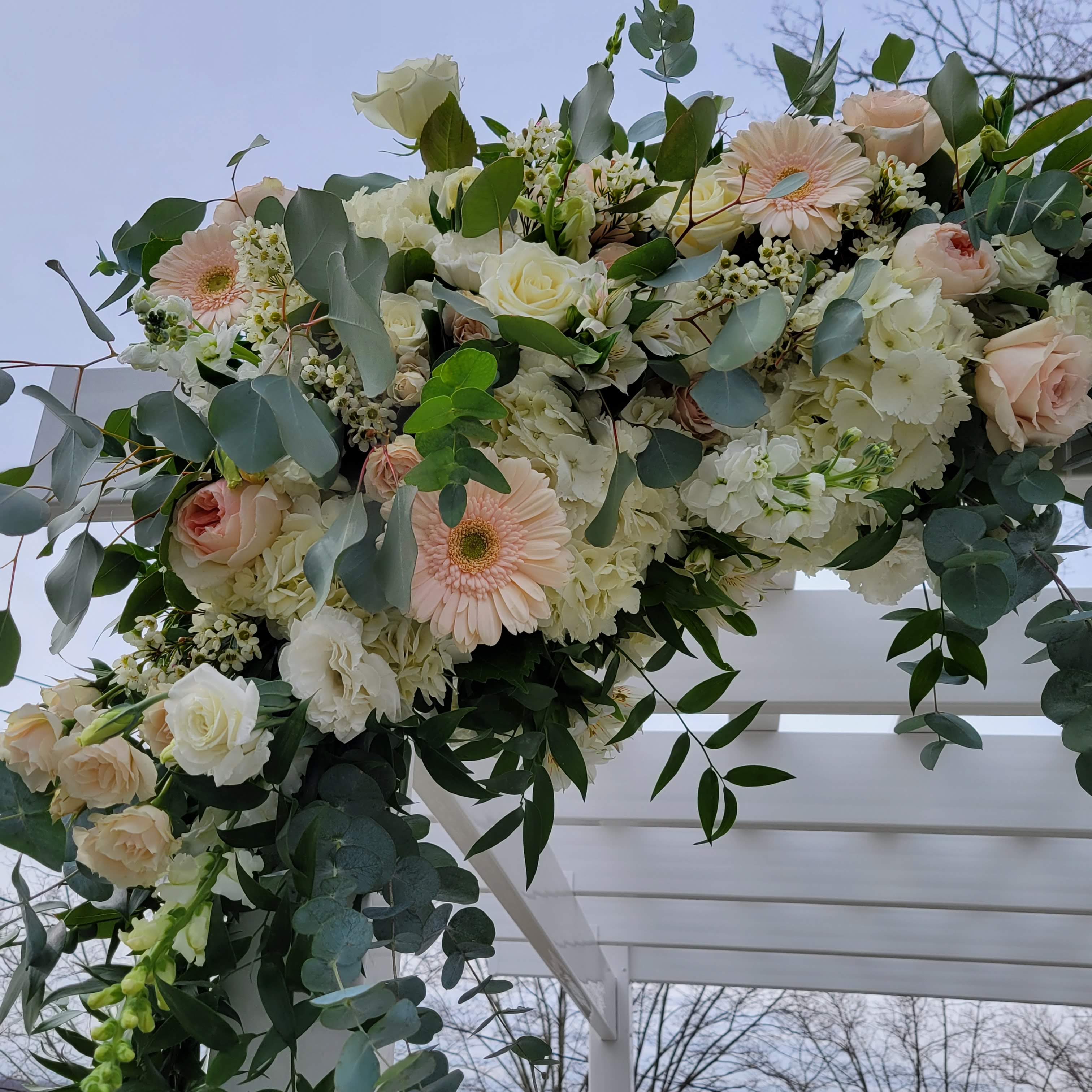 March wedding ceremony arch with spring flowers in a neutral color palette at Seacliff Manor, Seacliff NY. Roses, hydrangea, gerbera daisies, garden roses, spray roses, lisianthus, and eucalyptus.