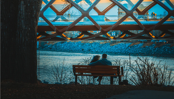 A couple cozying up on a bench near Calgary's landmark Peace Bridge.