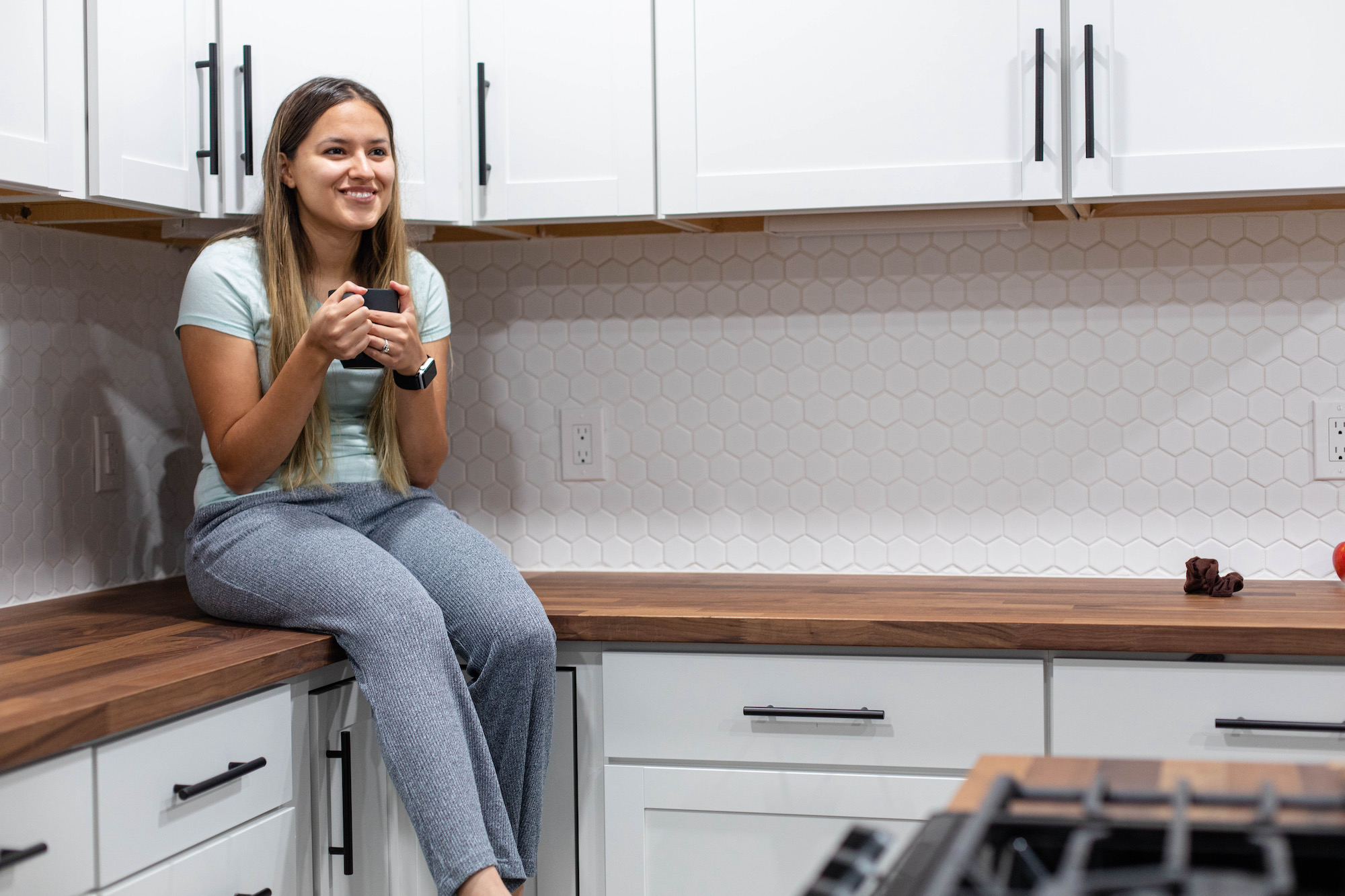 Woman enjoying a kitchen after a cabinet painting service in Hingham