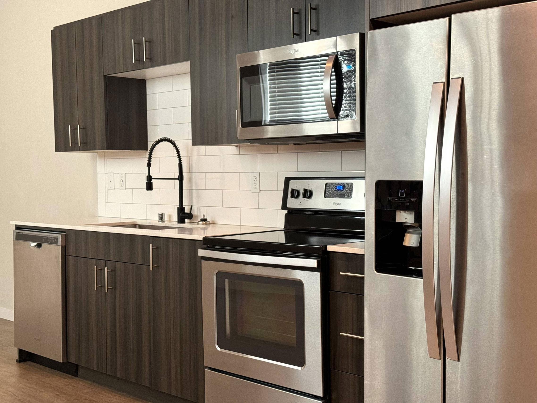 A modern kitchen with a stainless steel refrigerator and oven.