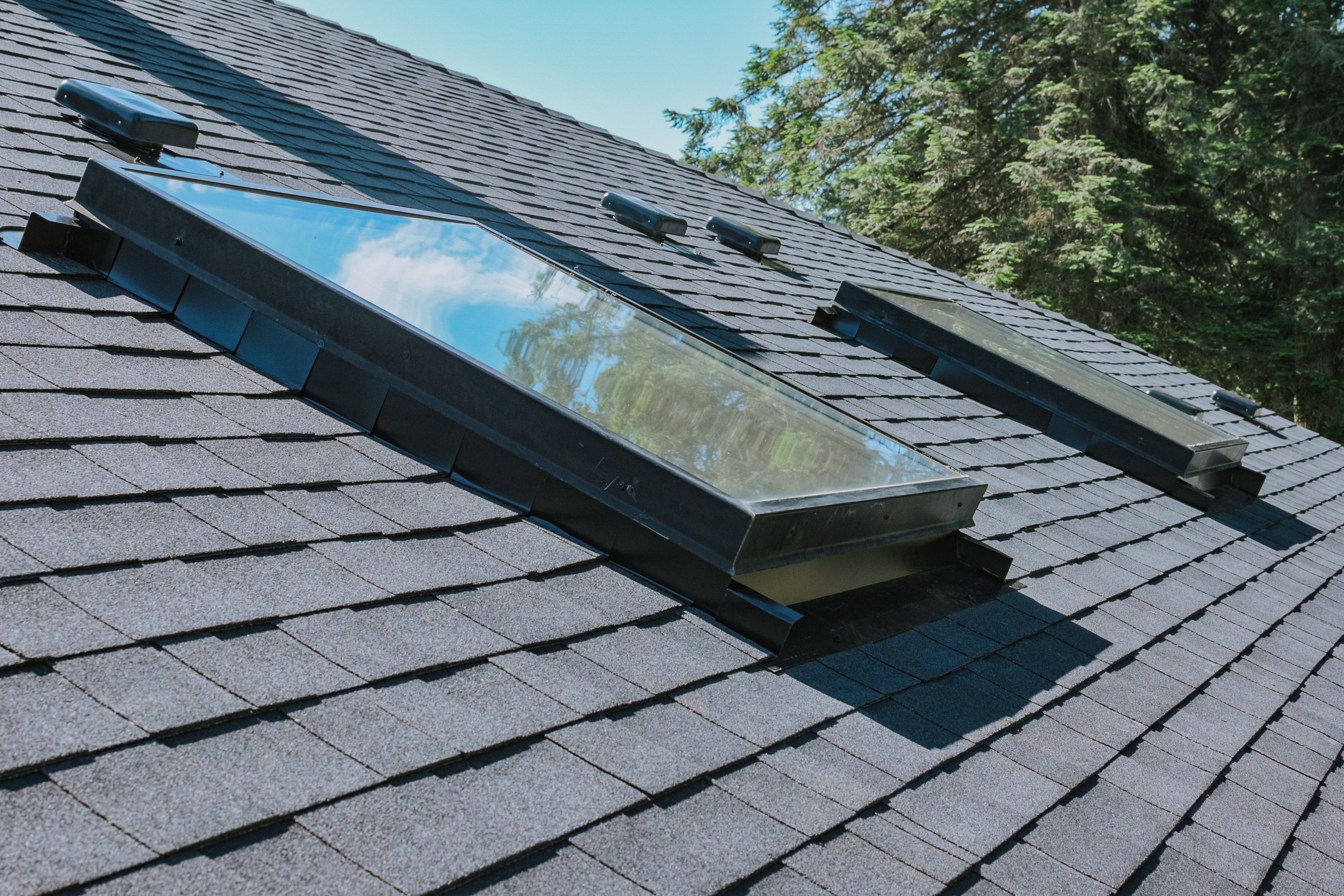 Residential asphalt shingle roof with multiple skylights installed 