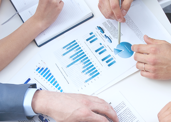 Close-up of several people at a table looking at paperwork and charts.