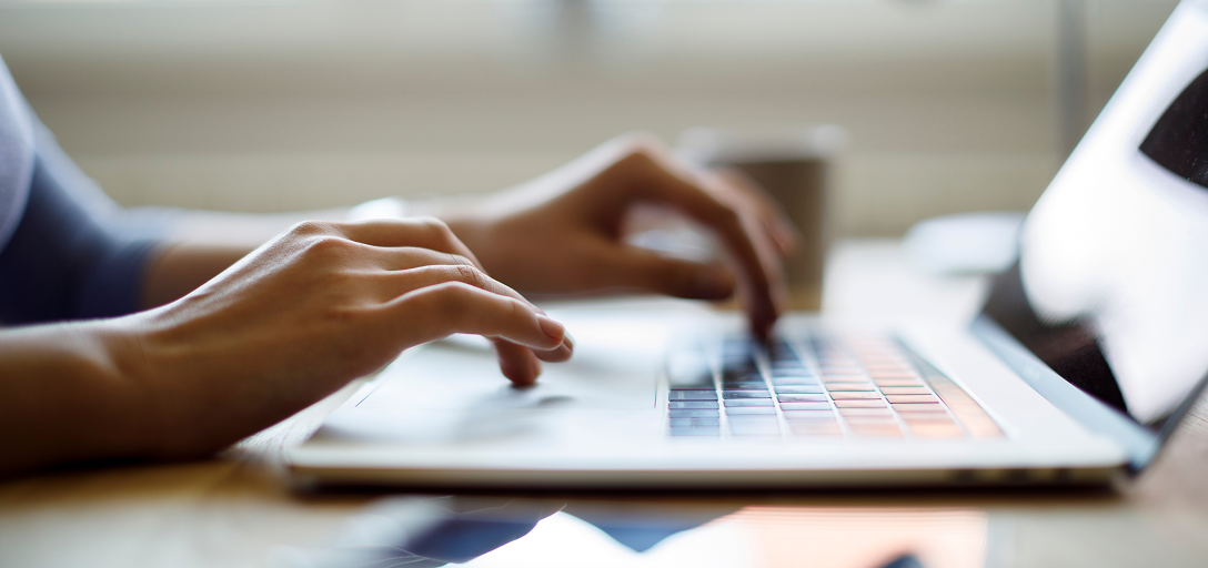 A close-up of an individual typing on their laptop.