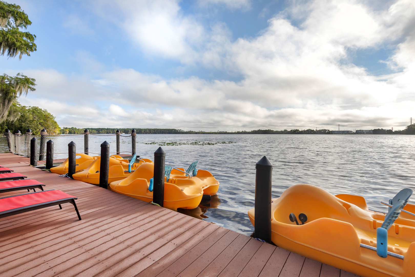 Three pedal boats line the lakeside dock at Bryan's Spanish Cove. The dock also features outdoor seating.