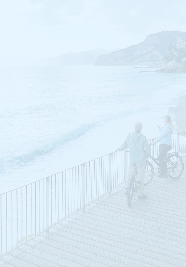 A couple on a bike ride enjoying the view of the ocean from the boardwalk.
