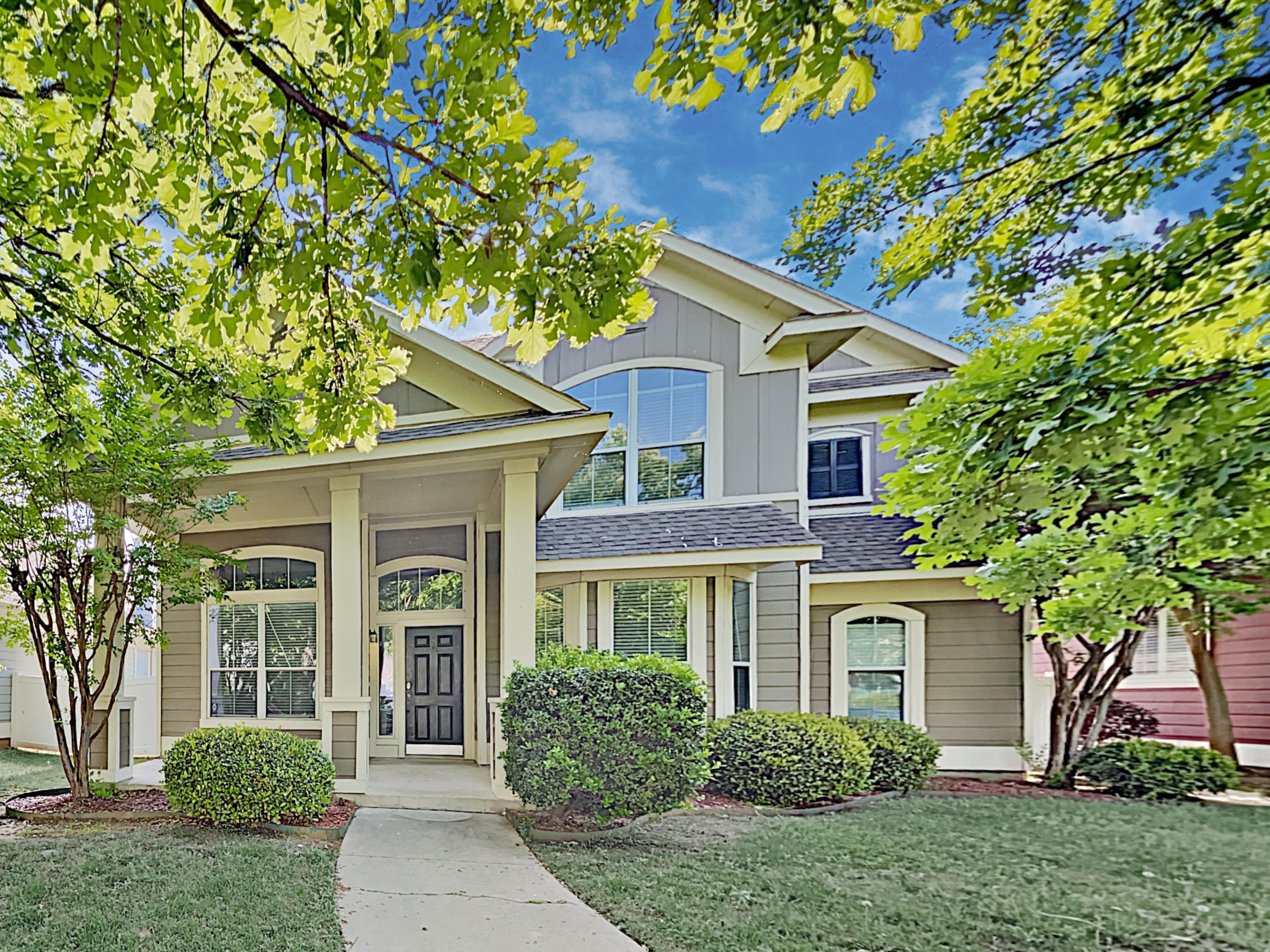 Charming home with a covered patio and beautiful landscaping at Invitation Homes Houston.