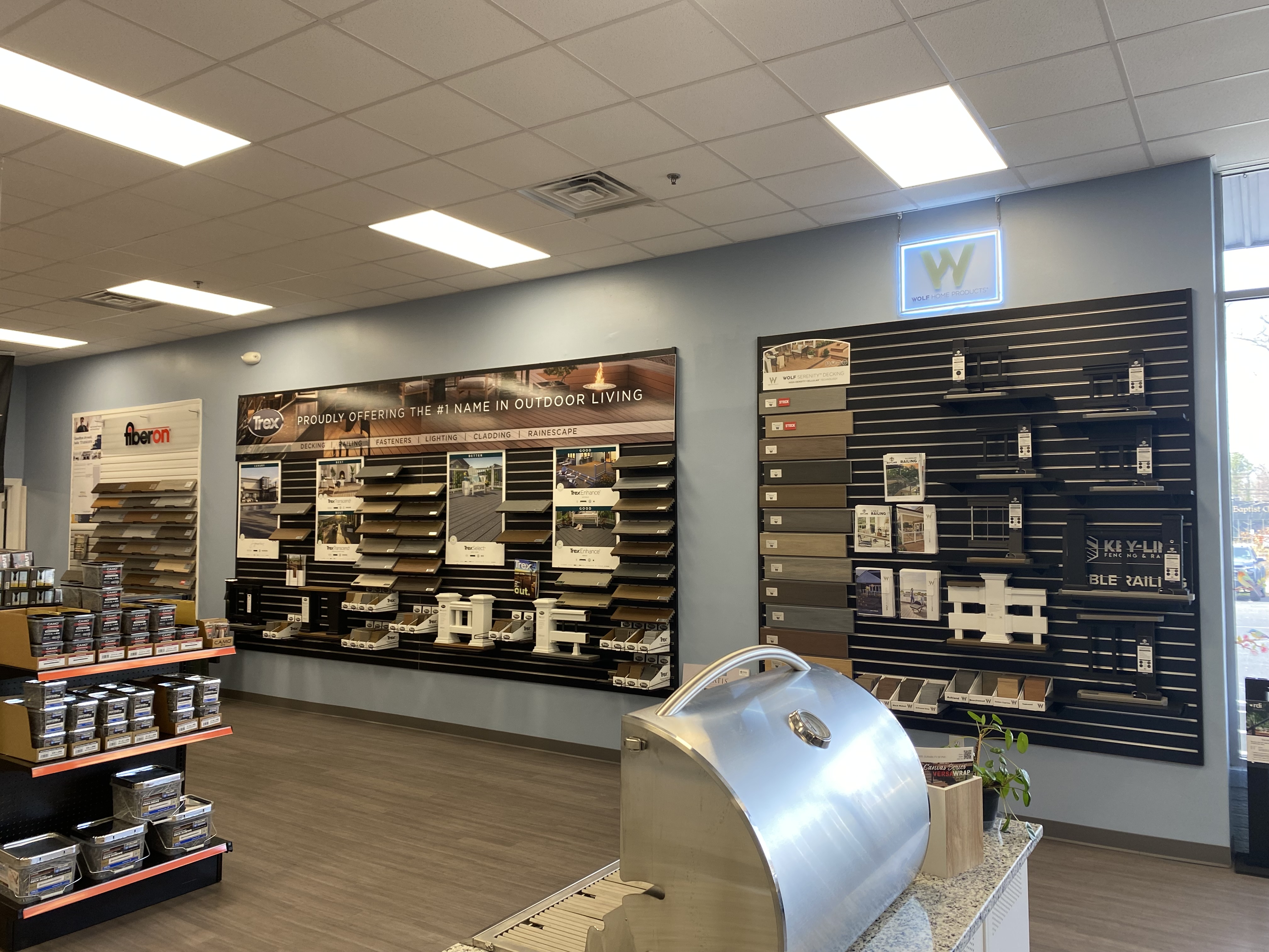 A showroom wall at Builders FirstSource showcasing Trex decking options, railing systems, and other outdoor building materials. The display includes a variety of composite and wood decking samples from top brands, offering solutions for customized outdoor living spaces.