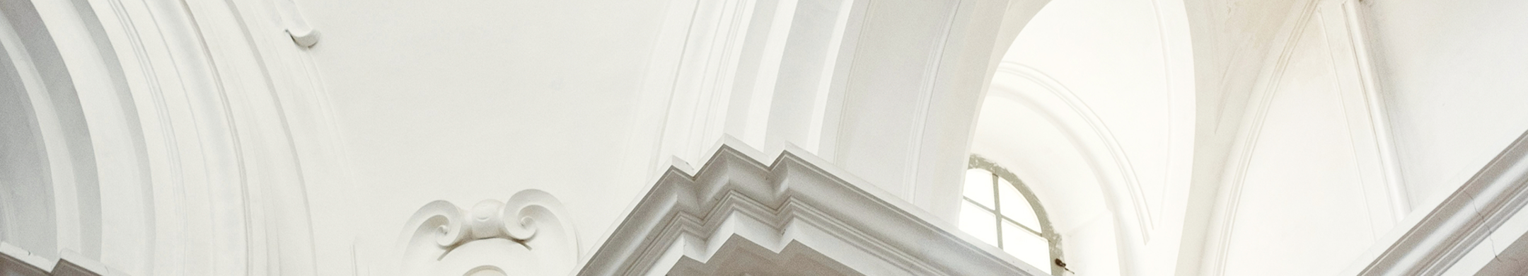 A white, arched ceiling in a grand building with a small window.