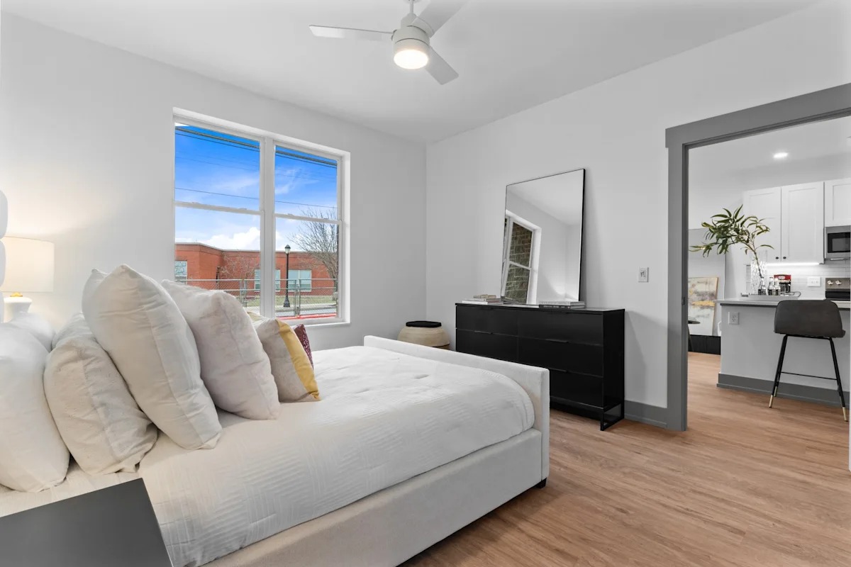 A bedroom with a large bed and a dresser with a mirror. 