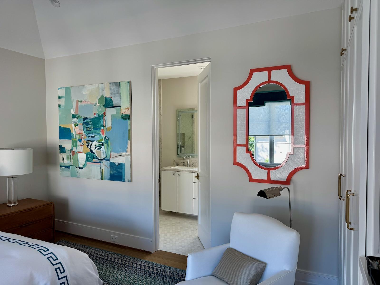 Abstract wall art and a decorative red framed mirror professionally installed on a bedroom wall in a River Oaks, Houston home.