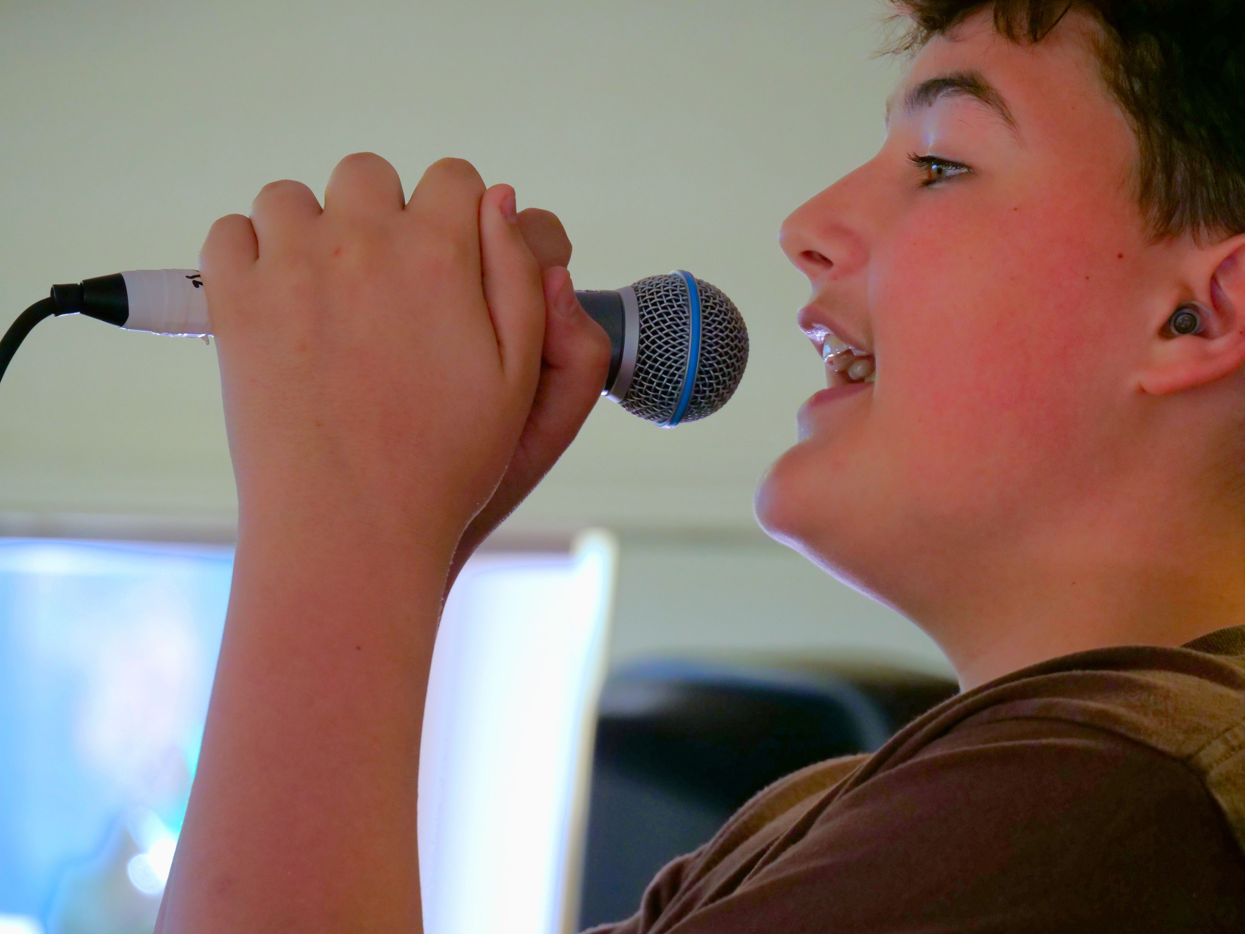 Young vocalist practicing singing during a performance-based music class.