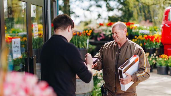 Una florista firma una entrega de un conductor de UPS.