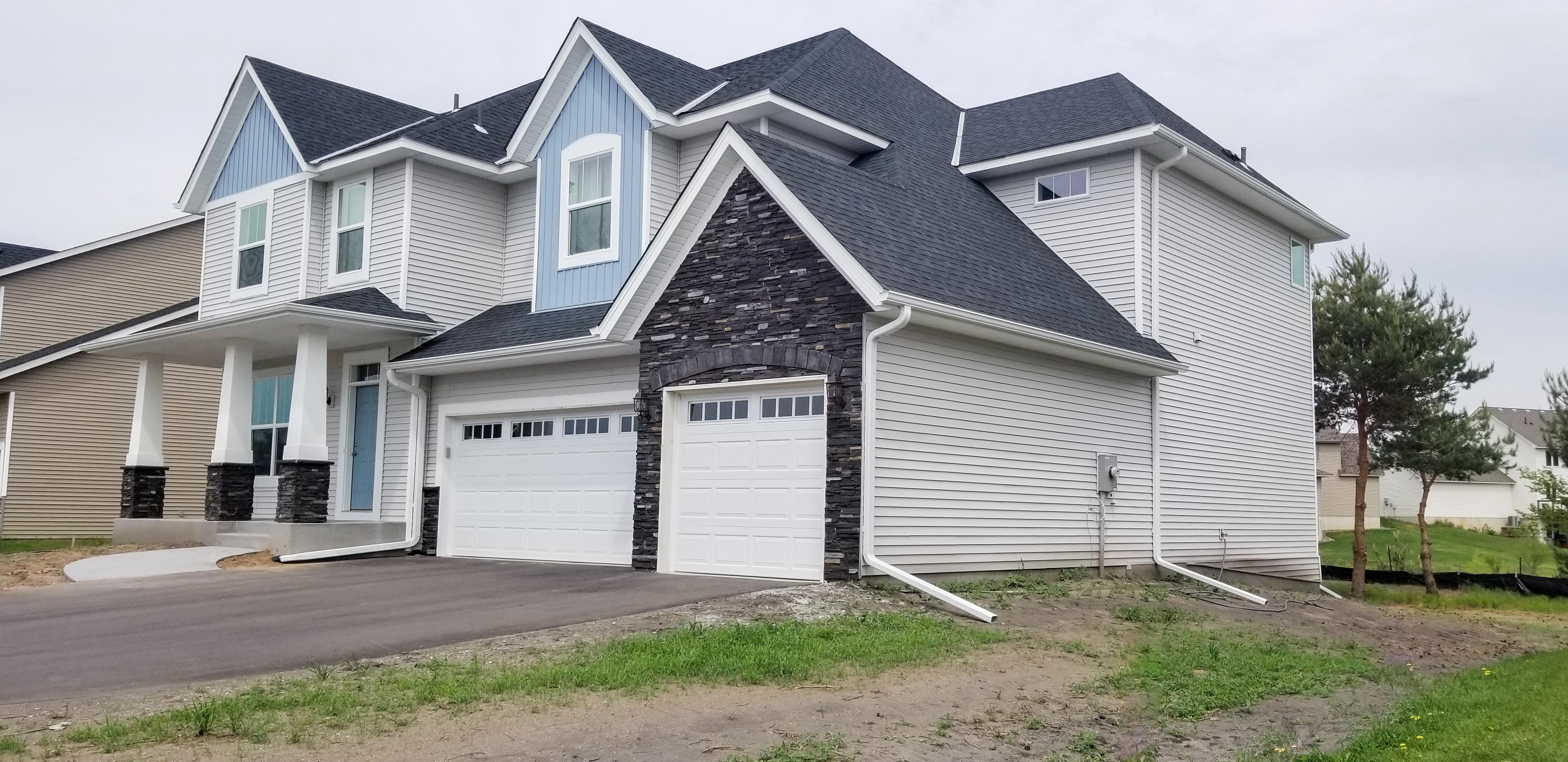 Complete white seamless gutter system and downspouts installed on a modern, multi-level home by Ultimate Gutter Solutions.