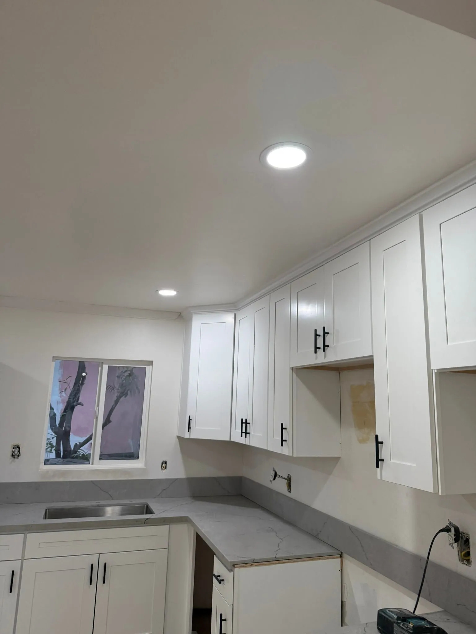 Modern kitchen renovation featuring white shaker cabinets, recessed lighting, quartz-style counterto 