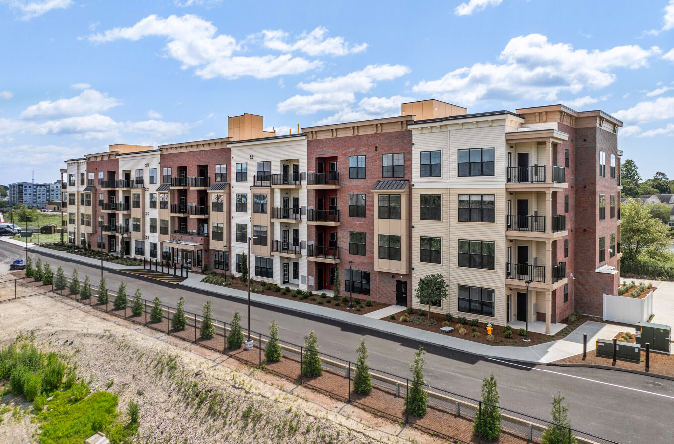 The multi-story exterior of Creekline at Fairfield apartments showcases a modern blend of red brick and light-colored siding.
