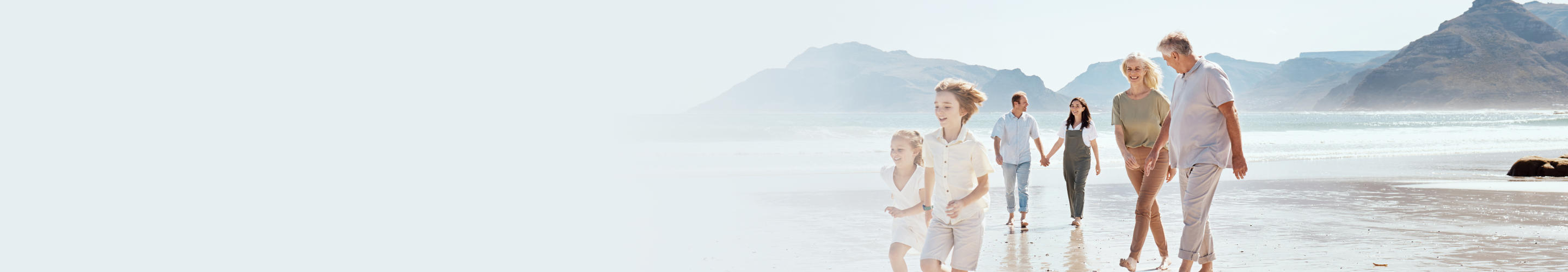 A multigenerational family walking along the beach together.