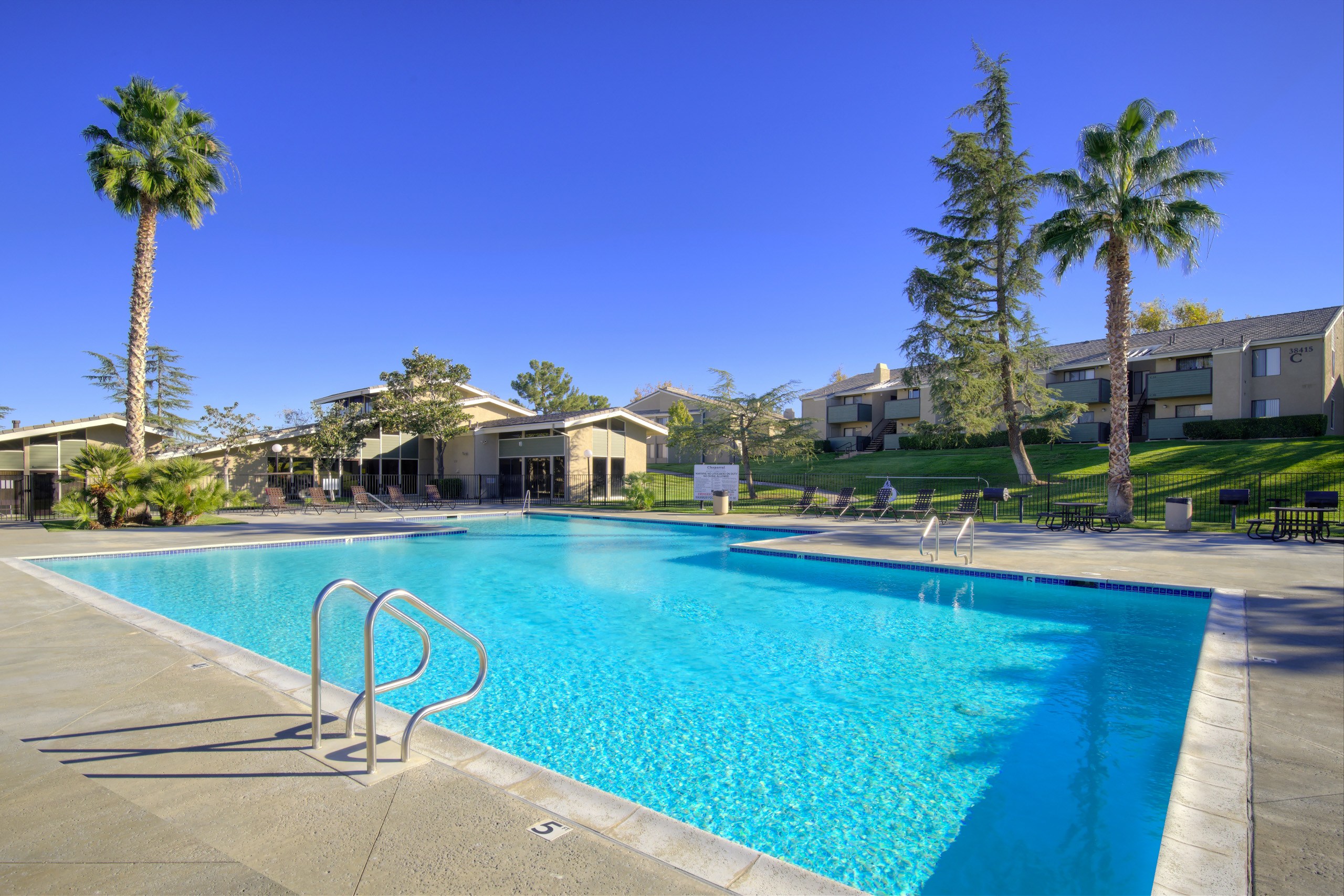 A swimming pool surrounded by palm trees and apartment buildings.