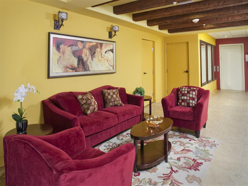 Living room with yellow walls and red furniture at The Verandas in Canoga Park