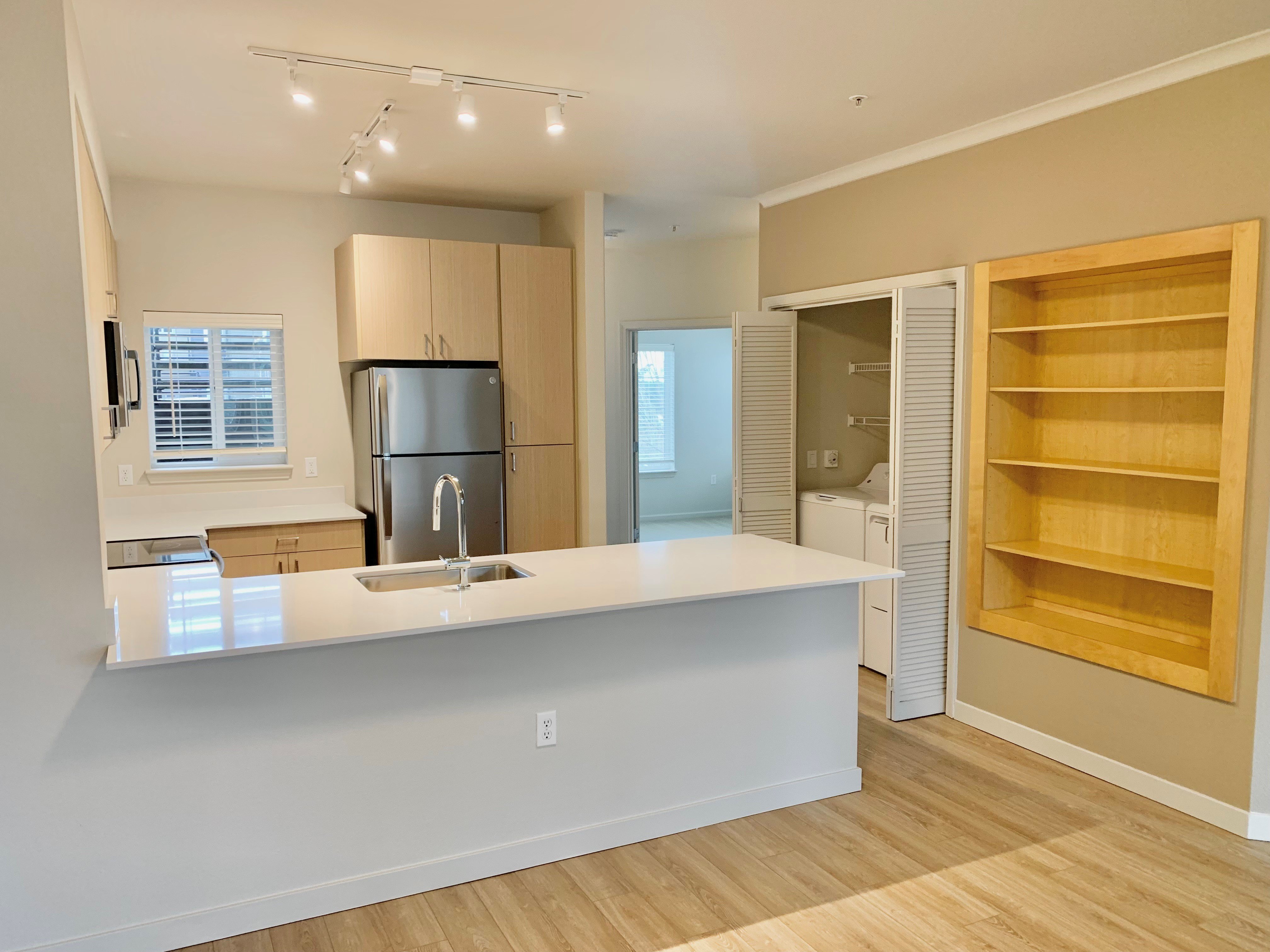 A kitchen with a white countertop and wooden flooring