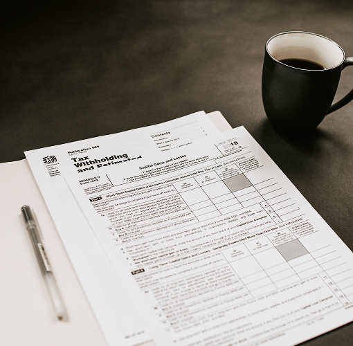 A series of financial documents next to a cup of coffee.