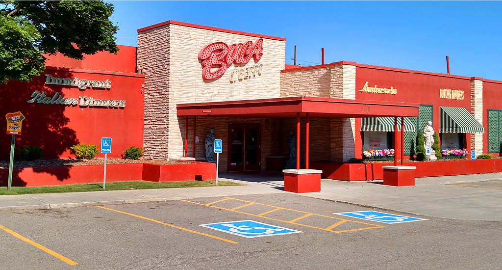 Buca di Beppo Fort Union showing red walls and white brick accent and flowers along the windows.